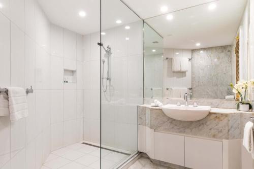 a white bathroom with a sink and a shower at Mirage Resort Villa 169 with access to Sheraton Facilities in Port Douglas