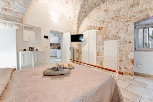 een slaapkamer met een bed in een kamer met een stenen muur bij Maison de Antonelle in Ostuni