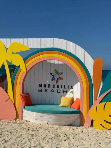 a bed on the beach with a rainbow painted on it at قرية مارسيليا بيتش فور in Sīdī ‘Abd ar Raḩmān