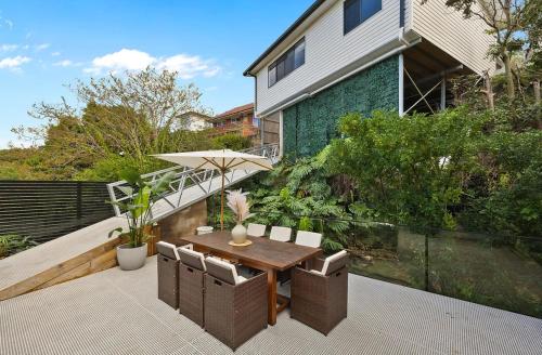 a wooden table with chairs and an umbrella on a patio at Affordable Luxury Stay Near Manly Beach in Sydney