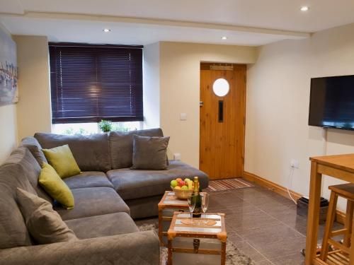 een woonkamer met een bank en een flatscreen-tv bij Rockfish Cottage in Brixham