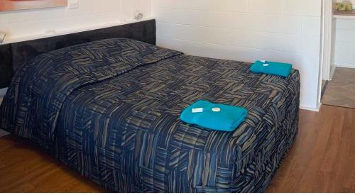 a bed with two blue bags sitting on top of it at Tropical City Motor Inn in Ayr