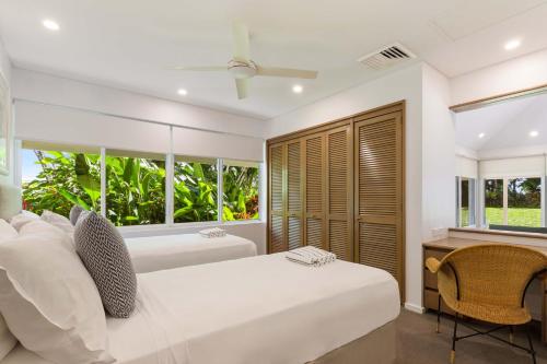 a bedroom with a bed and a desk and windows at Mirage Resort Villa 409 with access to Sheraton Facilities in Port Douglas