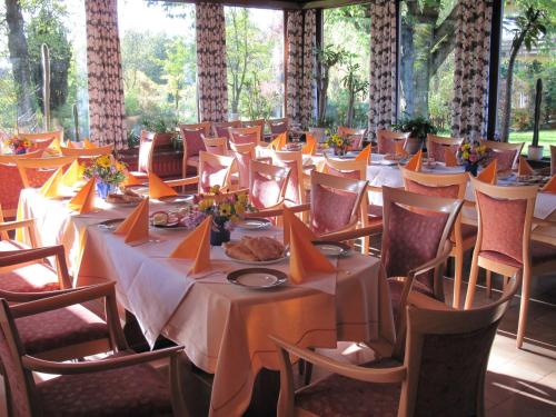 a row of tables with white tablecloths and orange napkins at Hotel-Café "Schauinsland" in Horn-Bad Meinberg