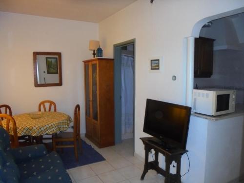 a living room with a tv and a table with a microwave at Casas da Barroca in Lagos
