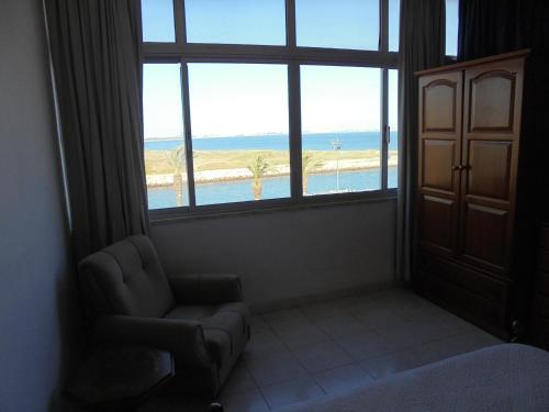 a room with a chair and a window with a view of the beach at Casas da Barroca in Lagos