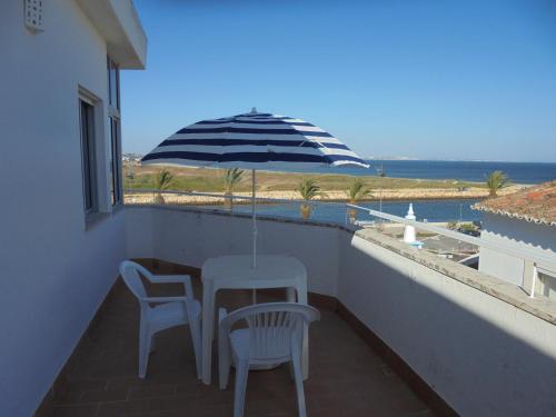 a table and chairs on a balcony with an umbrella at Casas da Barroca in Lagos
