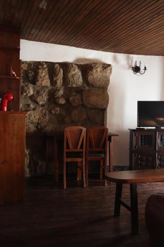 a room with two chairs and a table and a stone wall at Casa da Porta da Vila in Nisa