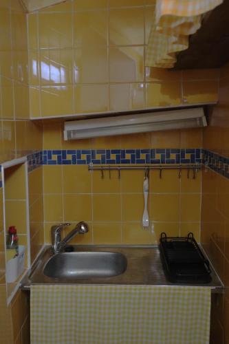 a sink in a kitchen with yellow tiles at Casa da Porta da Vila in Nisa