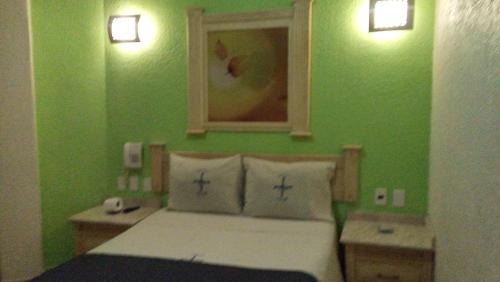 Dormitorio verde con cama y espejo en Hotel Astur, en Guadalajara