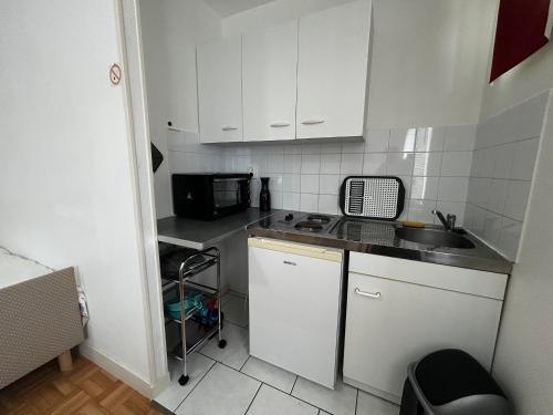 une petite cuisine avec un évier et un micro-ondes dans l'établissement Studio entre Thermes et centre-ville avec jardin, parking et WIFI - FR-1-541-119, à La Roche-Posay