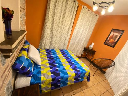 a bedroom with a bed with a blue and yellow blanket at Hotel y Restaurante San Fernando. in Jocotenango
