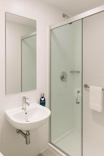 a bathroom with a sink and a glass shower at Stop Inn Antonio Carlos in Belo Horizonte