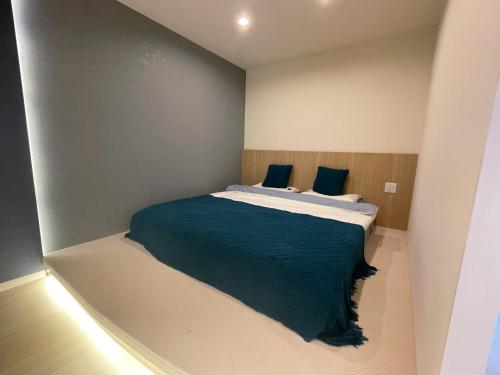 a small bedroom with a bed with blue sheets at アロハ鎌倉 in Kamakura