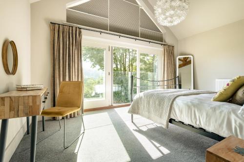 a bedroom with a bed and a chair and a window at Take Five in Ambleside