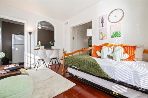 1 dormitorio con cama, mesa y reloj en Springtime Oasis Sun Kised 1BR Near UofA, en Tucson