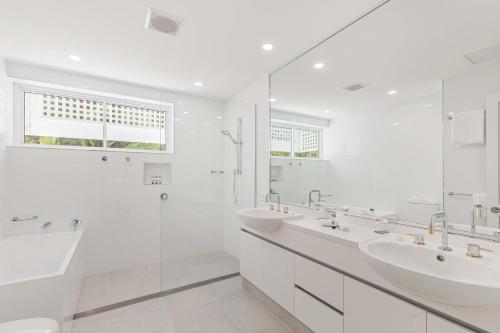 a white bathroom with two sinks and a shower at Mirage Resort Villa 456 with access to Sheraton Facilities in Port Douglas