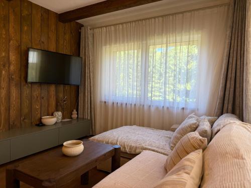 a bedroom with two beds and a tv on the wall at Bradutul de la munte Chalet in Braşov