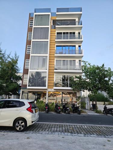 a white car parked in front of a building at Nala Host - 2BR Apartment Seaside Bliss in Hulhumale