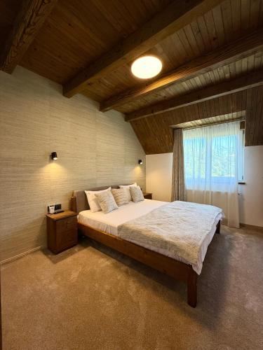 a bedroom with a large bed and a window at Bradutul de la munte Chalet in Braşov