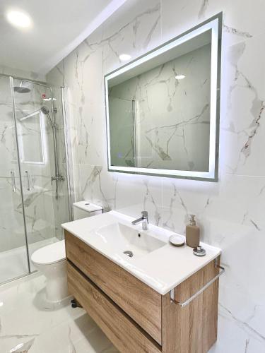 a bathroom with a sink and a toilet and a mirror at Figueira Luxury Comfort House in Figueira da Foz