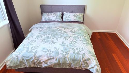 a bed with a blue and white bedspread on it at Nestled in Swan Valley area in West Swan