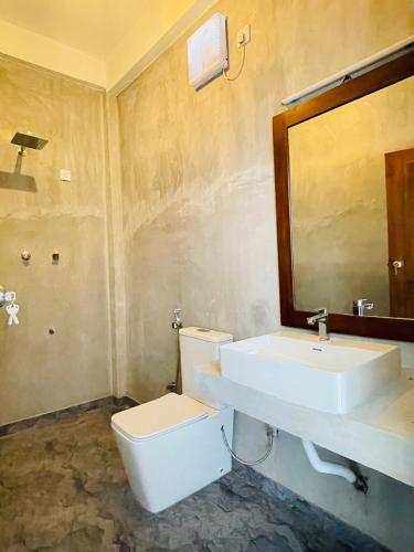 a bathroom with a white toilet and a sink at Doppel Gangs Arugambay in Arugam Bay