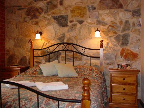 a bedroom with a bed and a stone wall at Langmeil Cottages in Tanunda