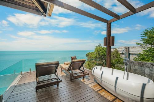 a bathroom with a tub and two chairs on a deck at The Kala in Amphoe Koh Samui