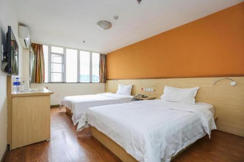 成都7 Days Inn Chengdu North Railway Metro Station的橙色墙壁的酒店房间里有两张床