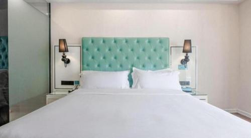 a bedroom with a large white bed with a blue headboard at Xana Lite Anqing Yuexi Swan Squre Branch in Yuexi