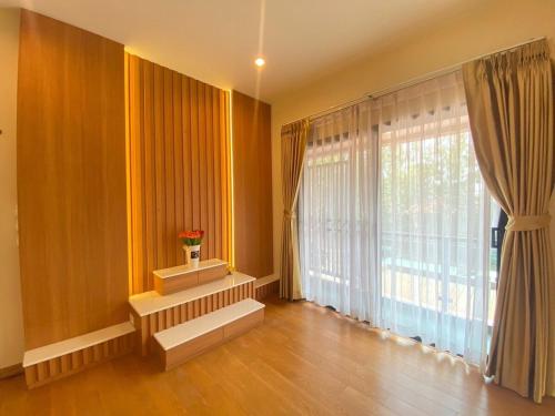 a living room with a large window with a vase of flowers at ทรีส์เฮาส์ Tree's House in Udon Thani