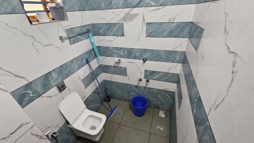 a bathroom with a toilet and a blue trash can at Kakapoo Homestay in Pālayangadi
