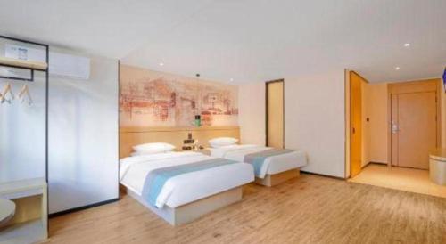 a bedroom with two beds and a painting on the wall at City Comfort Inn Kunming High Speed Railway South Station Yongxin Harvard in Kunming