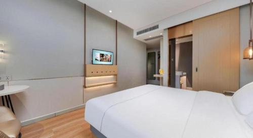 a bedroom with a large white bed and a television at Magnotel Hotel Xiamen North Station Binhai in Xiamen