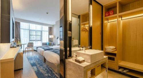 a bedroom with a bed and a bathroom with a sink at Echarm Hotel Hefei West Qilitang Metro Station in Hefei