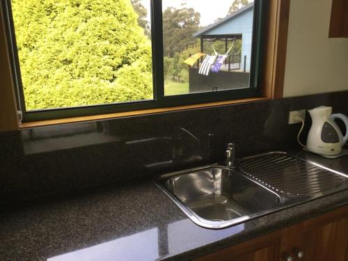 a kitchen counter with a sink and a window at Cabin in the Tasmanian Bush - Tranquility! in Pipers River