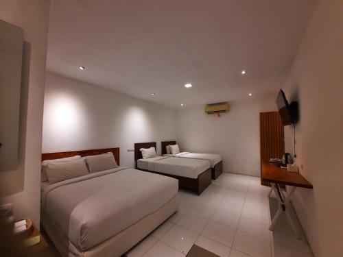 a hotel room with two beds and a television at Cactus Guest House Borobudur in Borobudur