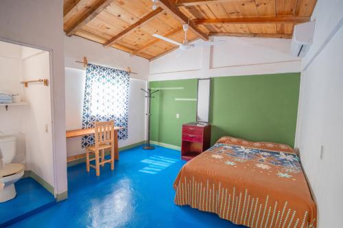 a bedroom with a bed and a table and a chair at Mahue Rooms and Camping in Puerto Escondido