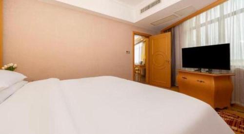 a bedroom with a white bed and a flat screen tv at Vienna Hotel Guangxi Fangcheng in Fangcheng