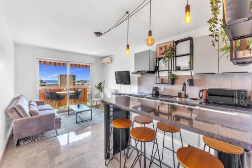 - une cuisine et un salon avec un comptoir et des tabourets dans l'établissement Bel appartement vue mer proche de la promenade des anglais, à Nice