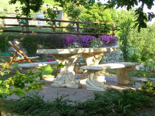 a stone bench and a table in a garden at Ariabuona in Moneglia