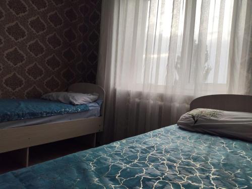 a bedroom with two beds and a window with curtains at RoomZoom in Karakol