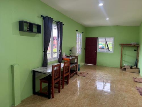 a living room with green walls and a table and chairs at Khao Sok Jungle Hostel in Khao Sok