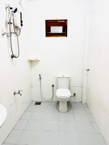 a white bathroom with a toilet and a sink at Ocean Villa in Trincomalee