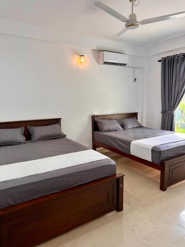 a bedroom with two beds and a ceiling fan at Ocean Villa in Trincomalee