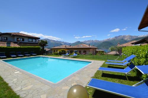 a swimming pool with blue chairs and mountains in the background at Villa Quattro Stagioni in Colico