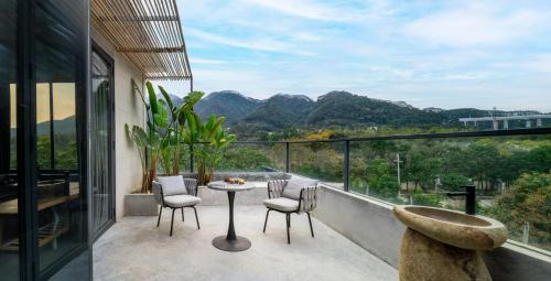 a balcony with a table and chairs and mountains at Qingyuan Zhilin Hot Spring Bed and Breakfast in Qingyuan