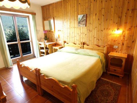 a bedroom with a bed and a table and a window at Hotel Alpe Fleurie in Champoluc