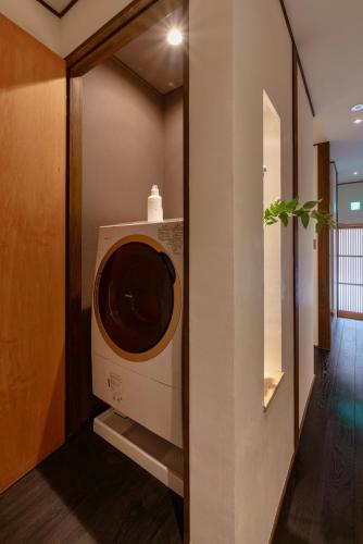 a washing machine in a room with a wall at Hinaya Higashiyama Machiya House in Kanazawa